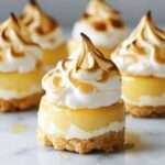 Mini cheesecakes au citron avec base biscuitée croustillante et meringue dorée légèrement caramélisée sur le dessus.