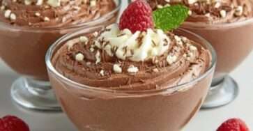 Mousse mascarpone au chocolat servie en verrine, texture aérienne et crémeuse, décorée de framboises fraîches, copeaux de chocolat et feuille de menthe.