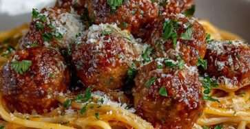 Assiette de spaghetti aux boulettes nappées de sauce tomate maison, avec parmesan râpé et persil frais, servie chaude.