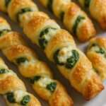 Torsades feuilletées dorées aux épinards et parmesan, croustillantes, servies sur une plaque avec une texture feuilletée visible.