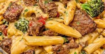 Assiette de penne crémeuses au bœuf et brocoli, avec morceaux de steak dorés, sauce au parmesan, persil frais et poivre noir.