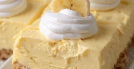 Cheesecake à la banane ultra crémeux présenté sur un plat, avec base de biscuits sablés, garniture onctueuse, chantilly et rondelles de banane fraîches.