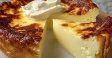 Gâteau au fromage ultra fondant doré au four, texture moelleuse et crémeuse, servi en part avec coulis de fruits et léger saupoudrage de sucre.