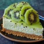 Cheesecake au kiwi sans cuisson avec base biscuitée croustillante, crème onctueuse et tranches de kiwi brillantes nappées de coulis fruité.