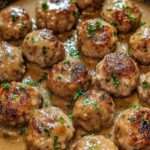 Boulettes de viande dorées nappées d’une sauce brune onctueuse, servies chaudes avec du persil frais dans une assiette généreuse.