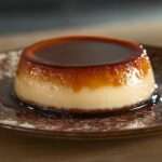 Flan caramel maison ultra fondant démoulé sur une assiette, nappé d’un caramel ambré brillant, avec une texture lisse, crémeuse et légèrement tremblotante.
