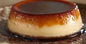 Flan caramel maison ultra fondant démoulé sur une assiette, nappé d’un caramel ambré brillant, avec une texture lisse, crémeuse et légèrement tremblotante.