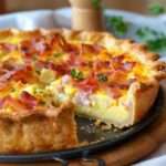 Quiche économique aux lardons dorée au four, avec pâte brisée croustillante et appareil crémeux, servie en parts avec une texture fondante.