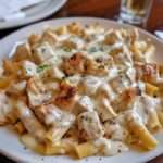 Assiette de pâtes au poulet nappées d’une sauce crémeuse au Boursin, avec morceaux de poulet dorés et persil frais, servie chaude.