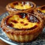 Pastéis de nata maison dorés, pâte feuilletée croustillante et crème onctueuse légèrement caramélisée avec des taches brunes typiques.