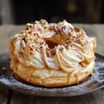 Paris-Brest en forme de couronne garni de crème pralinée, pâte à choux dorée avec amandes effilées et sucre glace.