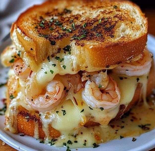 Croque-monsieur garni de crevettes crémeuses et fromage fondu, pain doré croustillant, servi chaud avec persil frais.