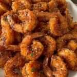 Crevettes panées croustillantes au parmesan et à l’ail, dorées à la perfection, servies avec persil frais et citron.