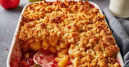 Crumble pommes et fruits rouges doré et croustillant, avec fruits fondants légèrement acidulés, servi chaud dans un plat avec texture sablée.