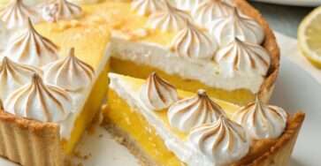 Tarte au citron meringuée maison avec crème citron lisse, meringue dorée et pâte sablée croustillante, présentée sur un plat élégant.