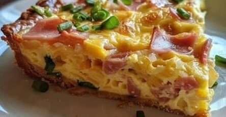 Quiche lorraine dorée avec pâte croustillante et garniture crémeuse aux lardons, découpée en parts et servie sur une assiette.