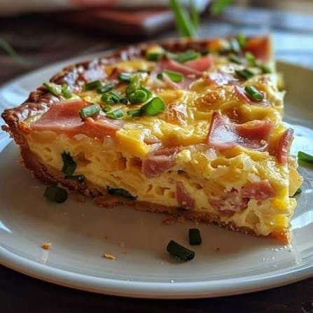 Quiche lorraine dorée avec pâte croustillante et garniture crémeuse aux lardons, découpée en parts et servie sur une assiette.