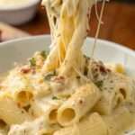 Pâtes crémeuses au poulet, ail et parmesan servies chaudes, avec sauce onctueuse, morceaux de poulet dorés et persil frais sur le dessus.