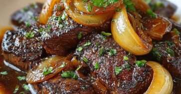 Sauté de bœuf aux oignons caramélisés nappé d’une sauce brillante, servi chaud avec du persil frais dans une poêle rustique.