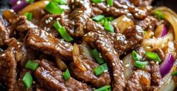 Assiette de sauté de bœuf aux oignons à la chinoise avec lamelles de viande brillantes, oignons légèrement caramélisés et sauce nappante, servie avec du riz blanc.