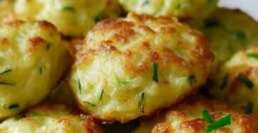 Petits nuages de courgettes au fromage cuits au four, dorés à l’extérieur et moelleux à l’intérieur, disposés sur une plaque avec herbes fraîches.