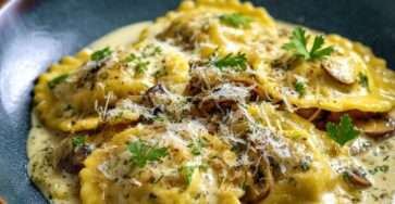 Ravioli maison farcis aux champignons nappés de sauce crémeuse au parmesan, servis dans une assiette creuse avec persil frais et fromage râpé.