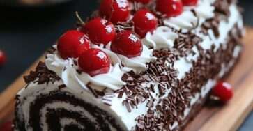 Gâteau roulé Forêt-Noire au chocolat garni de chantilly et cerises, décoré de copeaux de chocolat et sucre glace sur une assiette élégante.