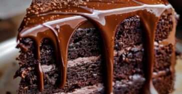 Gâteau au chocolat maison moelleux et fondant, légèrement craquelé sur le dessus, saupoudré de sucre glace et découpé en parts généreuses.