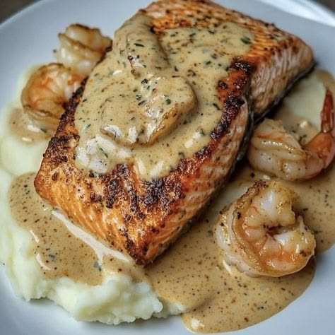 Pavé de saumon poêlé accompagné de crevettes nappées de sauce crémeuse, servi avec une purée de pommes de terre lisse et onctueuse.