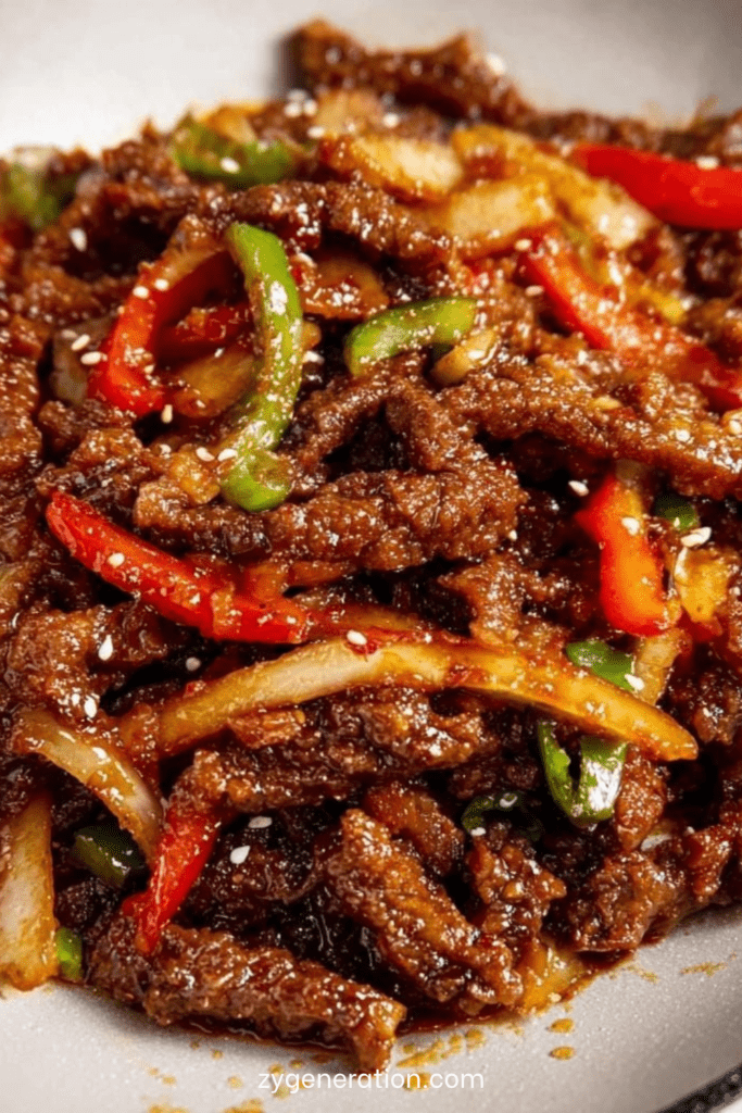 Lamelles de bœuf croustillant enrobées de sauce brillante sucrée salée avec poivrons rouges et verts, servies dans un wok fumant.