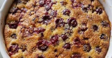 Clafoutis aux cerises maison doré et moelleux dans un plat rustique avec cerises fraîches et sucre légèrement caramélisé