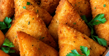Samoussas croustillants au fromage, dorés à la poêle, garnis d’une farce fondante à la mozzarella et au fromage frais, servis avec du persil.