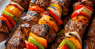 Brochettes de bœuf grillées avec poivrons rouges, jaunes et verts, oignons et marinade parfumée, servies avec du persil frais.