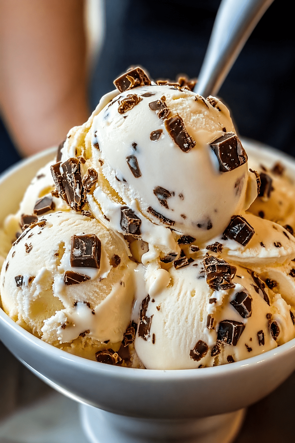 Glace vanille maison aux pépites de chocolat, servie en boules dans une coupe avec morceaux de chocolat et texture crémeuse.