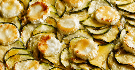 Tarte fine aux courgettes, chèvre et miel sur pâte feuilletée dorée, garnie de rondelles de courgettes, fromage de chèvre fondu et filet de miel.