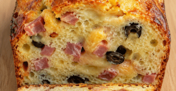 Cake salé jambon, olives et fromage coupé en tranches, avec une mie moelleuse, des morceaux d’olives, du jambon et du fromage fondu.