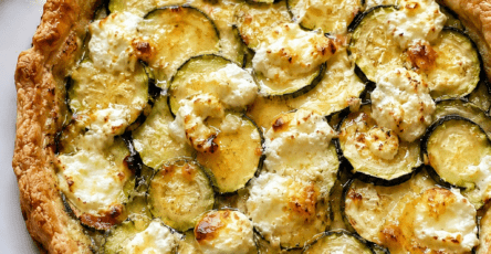 Tarte courgettes, chèvre et miel dorée au four, garnie de fines rondelles de courgettes, morceaux de fromage de chèvre fondant et filet de miel brillant.