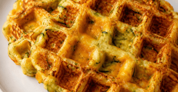 Gaufres salées courgette fromage bien dorées, croustillantes à l’extérieur, moelleuses à l’intérieur, servies avec une sauce au yaourt et des herbes fraîches.
