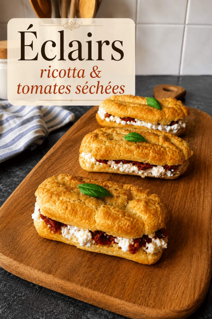 Éclair salé garni de crème de burrata à l’huile d’olive, de tomates confites rouges et de basilic frais, servi en bouchée apéritive.