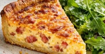 Quiche lorraine traditionnelle dorée, garnie de lardons fumés, servie en parts avec une pâte croustillante et une salade verte.