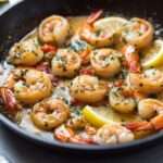 Poêlée de crevettes dorées au beurre à l’ail et au citron, parsemées de persil frais et servies avec du pain croustillant.