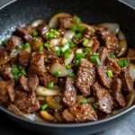Sauté de bœuf aux oignons à la chinoise servi avec riz blanc, lamelles de bœuf tendres, sauce brillante, ail, oignons fondants et ciboule fraîche