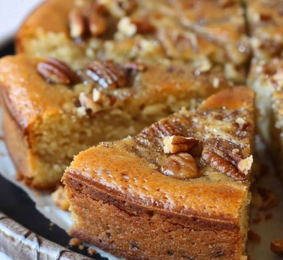 Gâteau léger aux noisettes moelleux, saupoudré de sucre glace, présenté en parts carrées avec une texture aérienne et dorée.