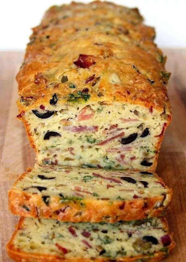Cake salé doré aux olives noires, olives vertes, bacon et fromage râpé, coupé en tranches moelleuses pour l’apéritif ou un buffet.