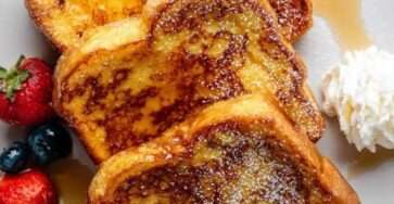 Tranches de pain perdu moelleux et doré, nappées de sirop d’érable, saupoudrées de sucre glace et servies avec fraises et myrtilles.