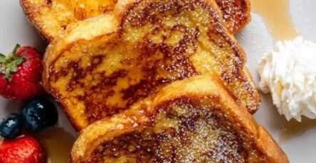 Tranches de pain perdu moelleux et doré, nappées de sirop d’érable, saupoudrées de sucre glace et servies avec fraises et myrtilles.