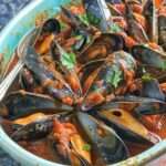 Moules fraîches à la sauce tomate épicée avec ail, oignon, paprika, vin blanc, piment, persil frais et sauce rouge parfumée.
