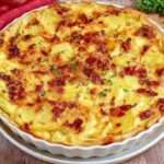 Tarte salée aux pommes de terre fondantes, lardons fumés dorés, crème fraîche, œufs et comté râpé gratiné sur pâte brisée.