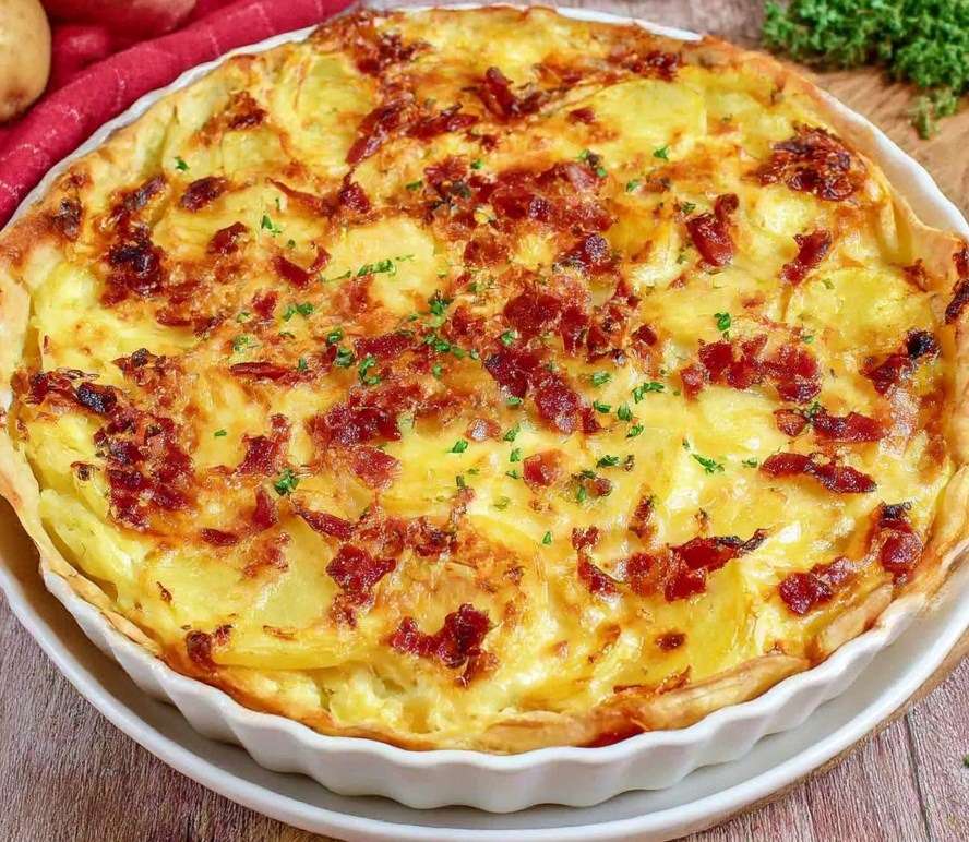 Tarte salée aux pommes de terre fondantes, lardons fumés dorés, crème fraîche, œufs et comté râpé gratiné sur pâte brisée.