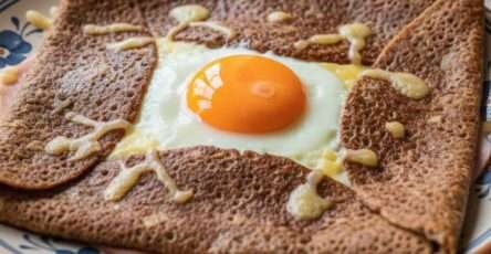 Galette complète bretonne au sarrasin garnie de jambon blanc, fromage râpé fondu et œuf au jaune coulant, pliée en carré.